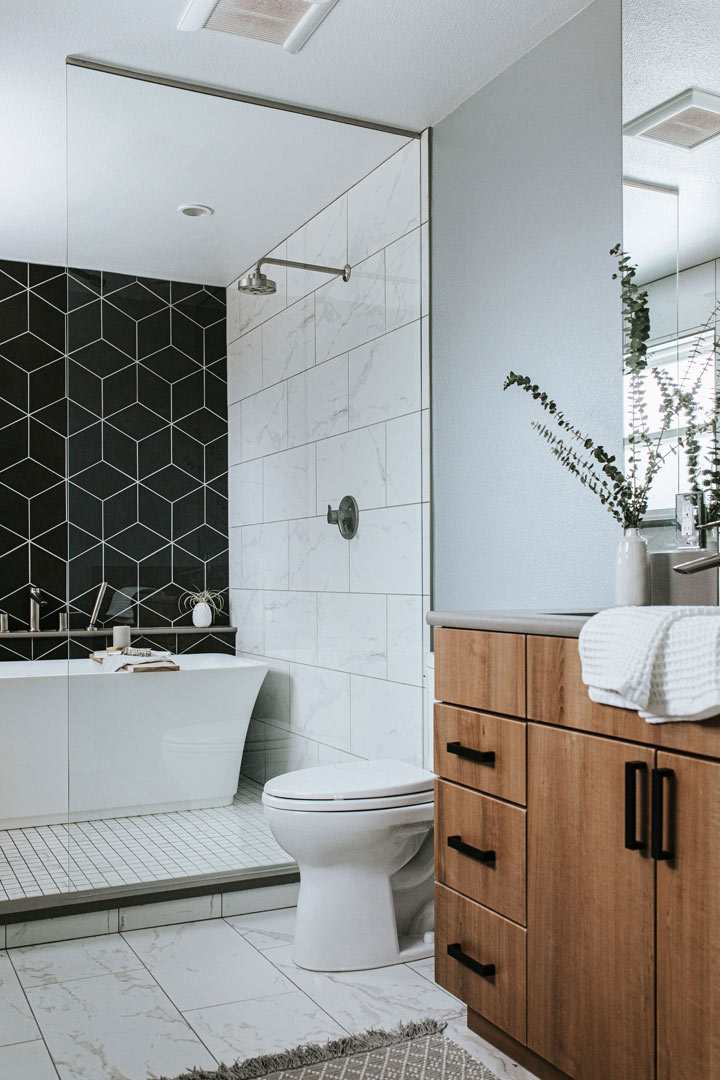 Natural wood vanity with matte black hardware marble floor tile and accent wall of geometric tile design by J. Reiko Design + Co