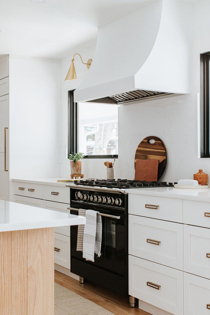 Modern Mostly White Kitchen with Light Wood Floors Black Windows and Range and Brass Sconces and Plumbing Interior Design by J Reiko Design + Co. 