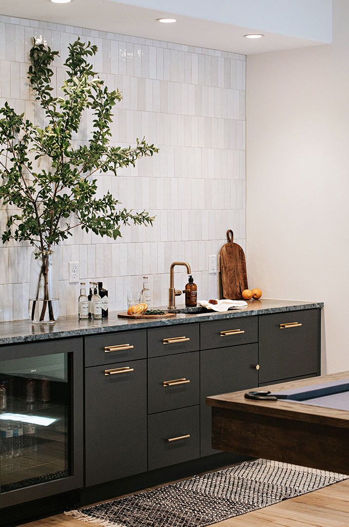 Industrial Modern Basement Bar with Dark Grey Cabinets, Brass Hardware, Soapstone Countertops and Bedrosians Cloe Tile Backsplash