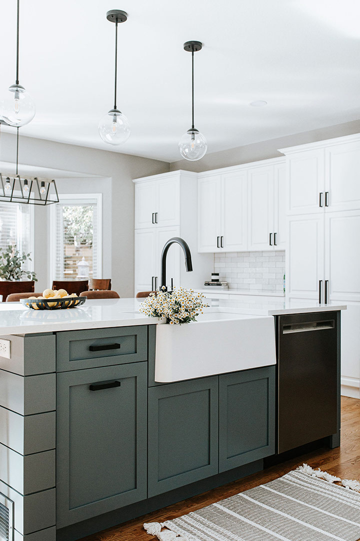 Jenny Murphy carefully selected a muted teal shiplap island below modern pendant lights bring a modern feel to this farmhouse kitchen.