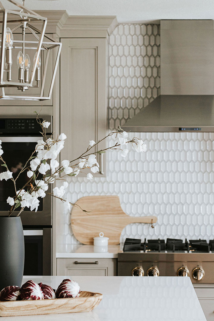 Jenny Murphy of J. Reiko Design + Co pairs a caged pendant light with neutral grey cabinets and a modern ceramic hexagon mosaic backsplash.