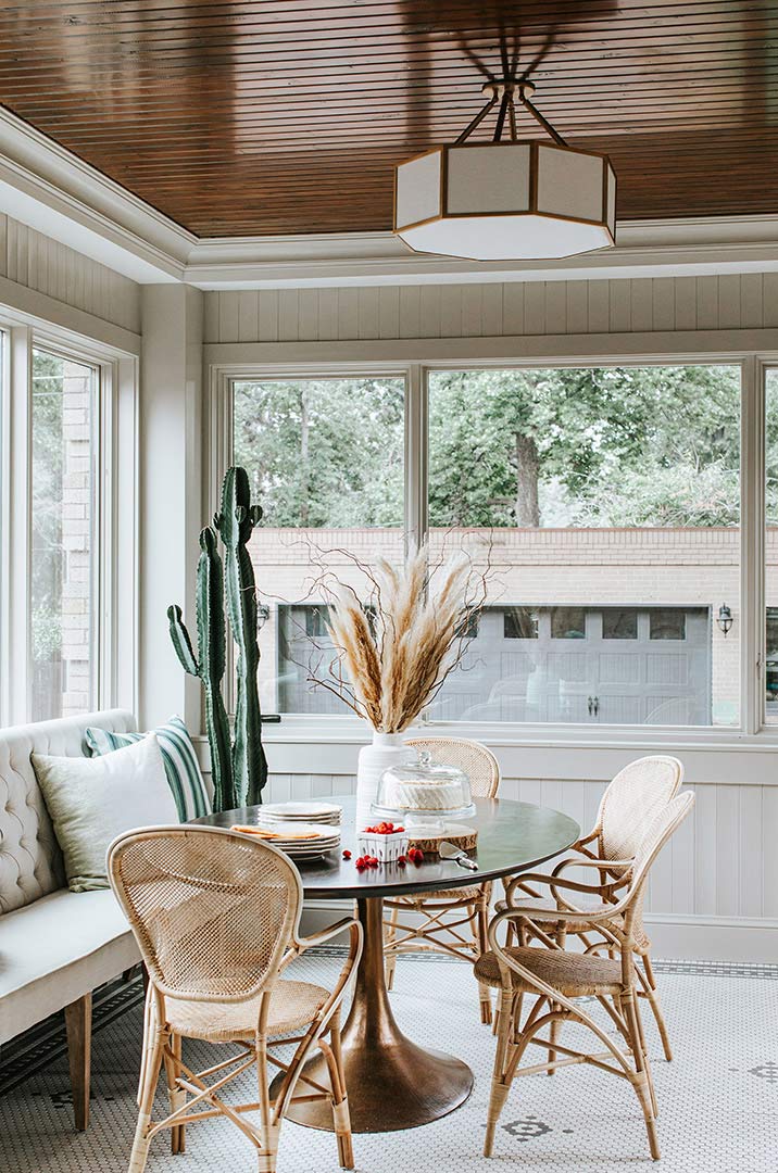 Traditional furniture is paired to make for a transitional vibe Jenny Murphy ties the wood toned rattan chairs with the wood paneled ceiling.