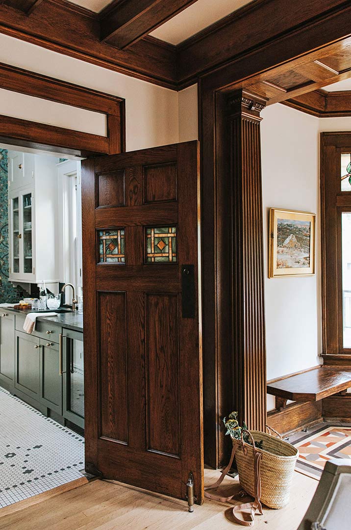 Tradtional dark stained wood trim, ceiling beams and door are accented by the butler's pantry and it's rich color and traditional mosaic tile flooring. 