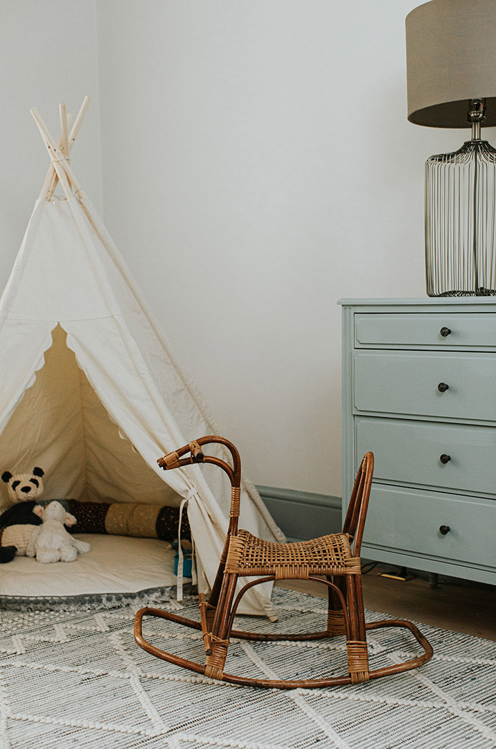 Green painted trim on a traditional remodel accent the natural fiber rugs, wicker rattan rocking horse and canvas children's play tee-pee. 