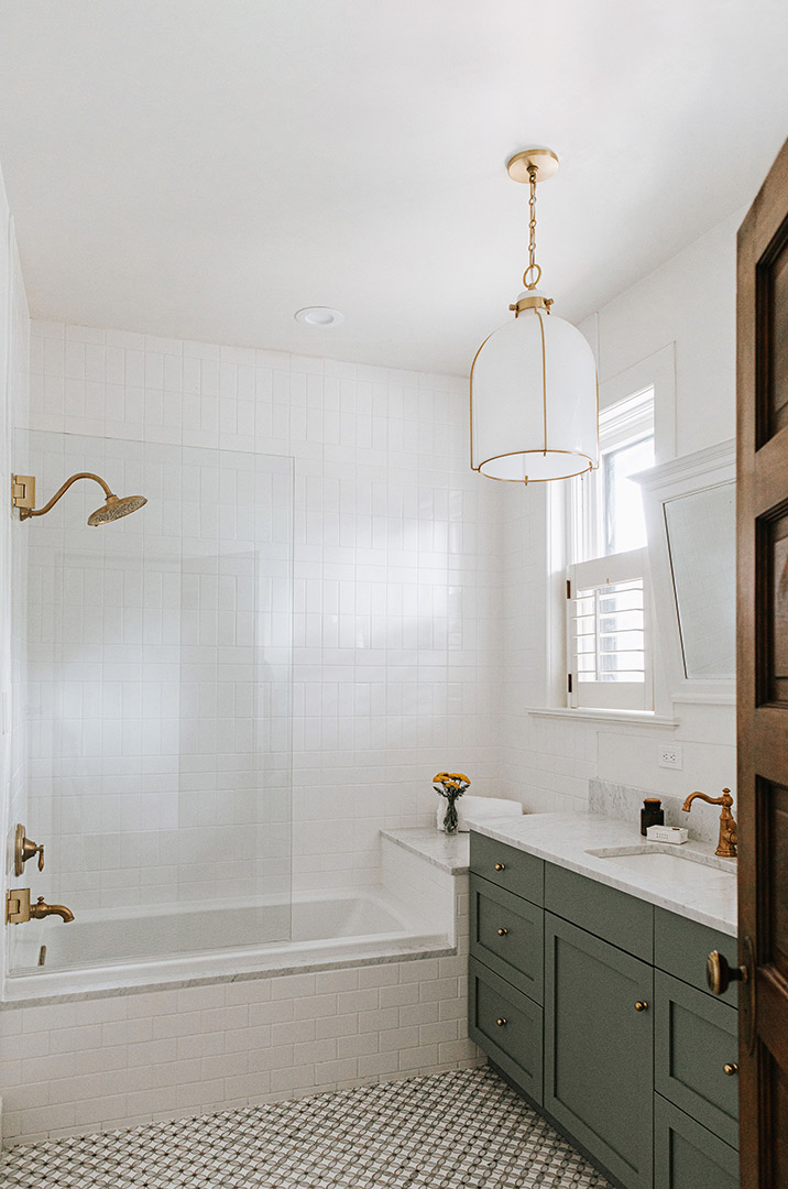 The second bathroom of the traditional remodel, features green cabinet vanity, brass hardware and plumbing fixtures.