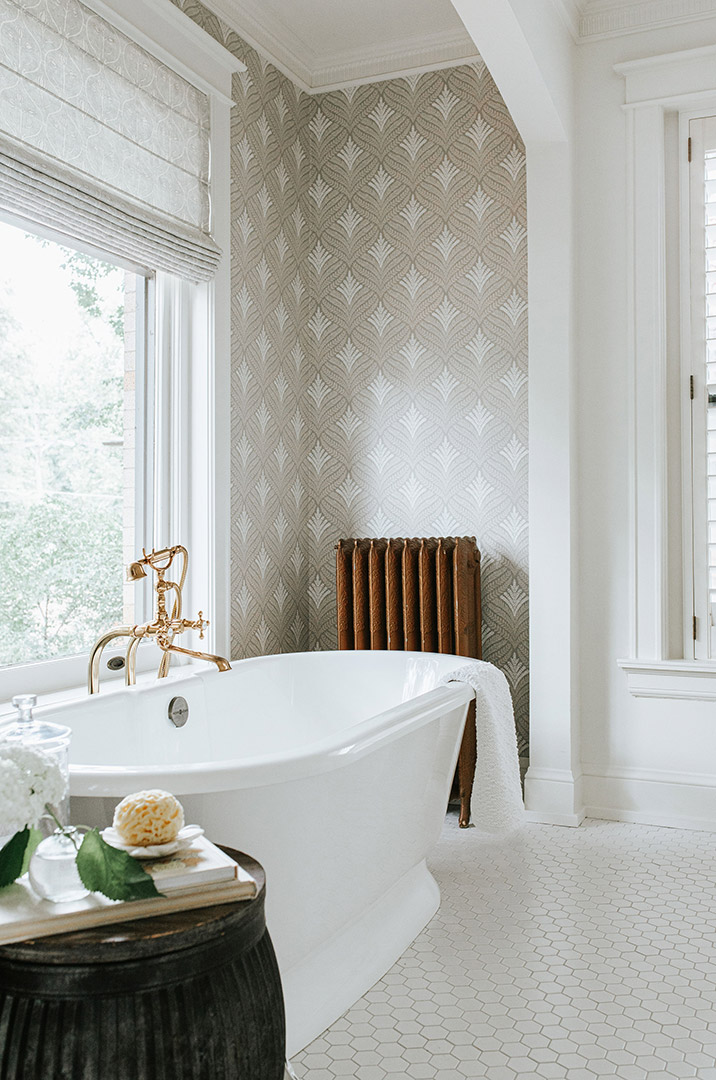 Newly renovated master bathroom with white hexagon tile flooring, traditional wallpaper, and a beautiful stand alone tub. 