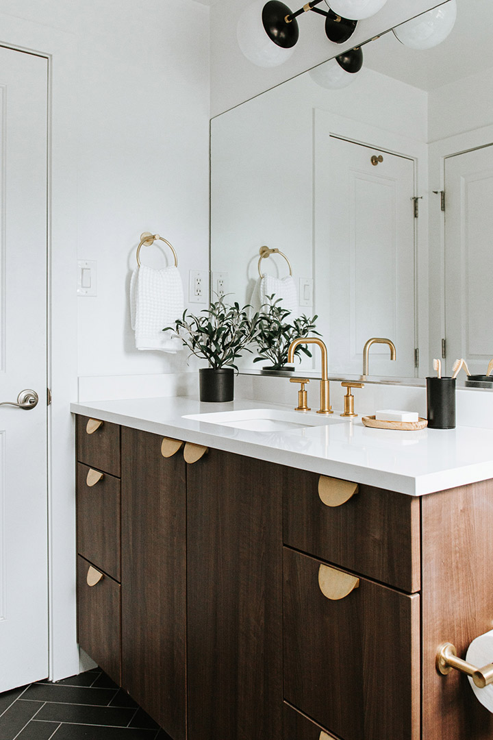 Fully Custom bathroom remodel with unique brass hardware and fixtures paired with a walnut vanity and herringbone black tile.