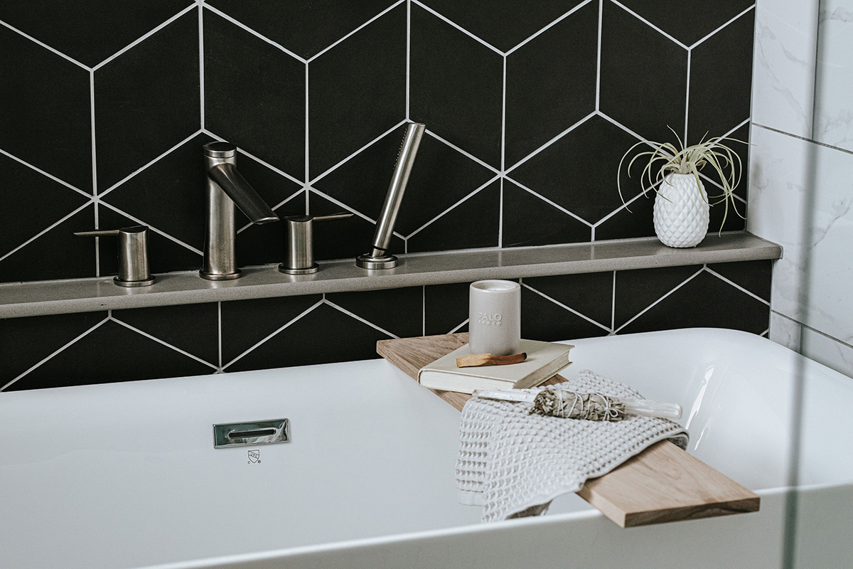 Close up photo of geometric black tile with white grout and modern ledge hardware. 