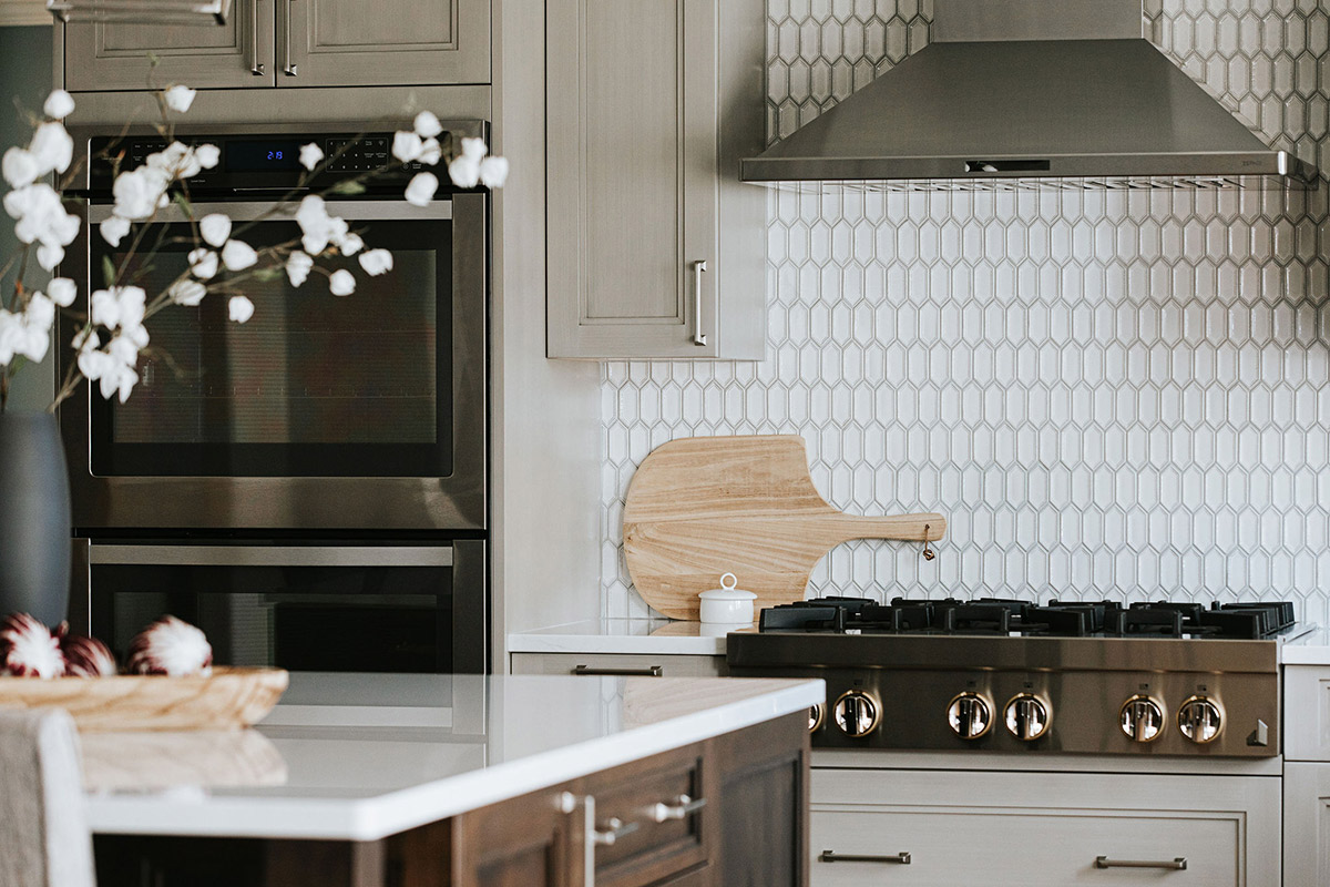 The ceramic hexagon mosaic backsplash designed by J. Reiko Design + Co accents the stainless steel appliances and brushed nickel hardware
