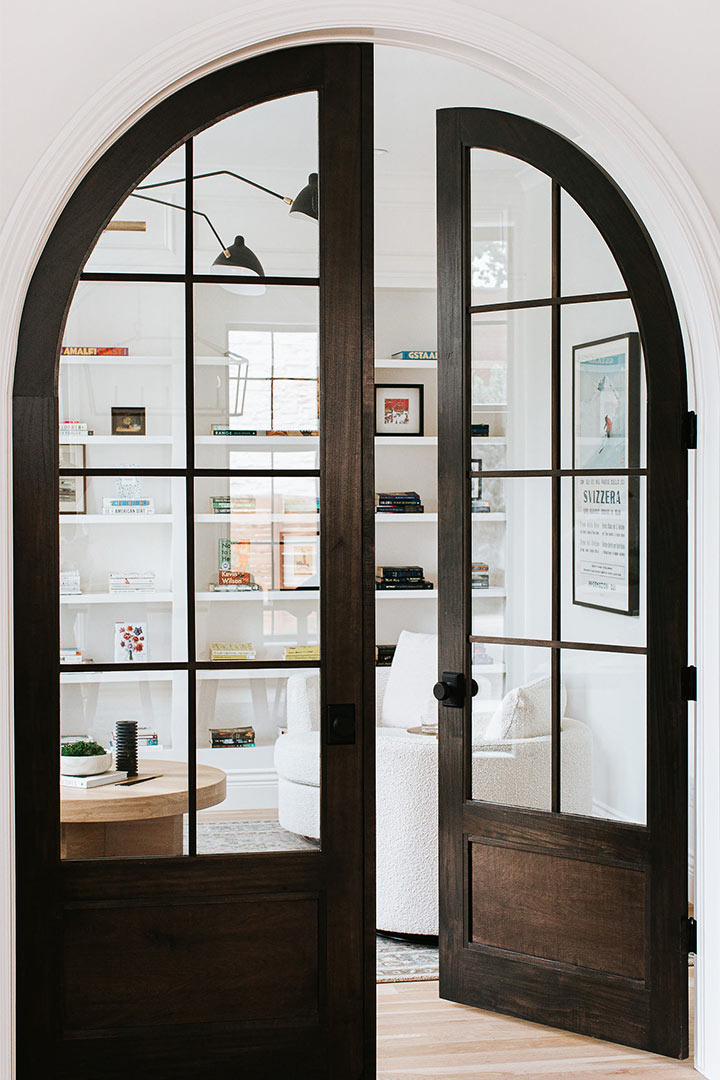 Black arched french doors frame a bright office with furniture and styling done by J.Reiko Design + Co. 