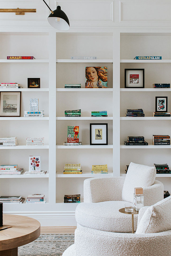 Bright white shelves of a modern built-in bookshelf are designed in a minimalist style by Jenny Murphy of J. Reiko Design + Co. 
