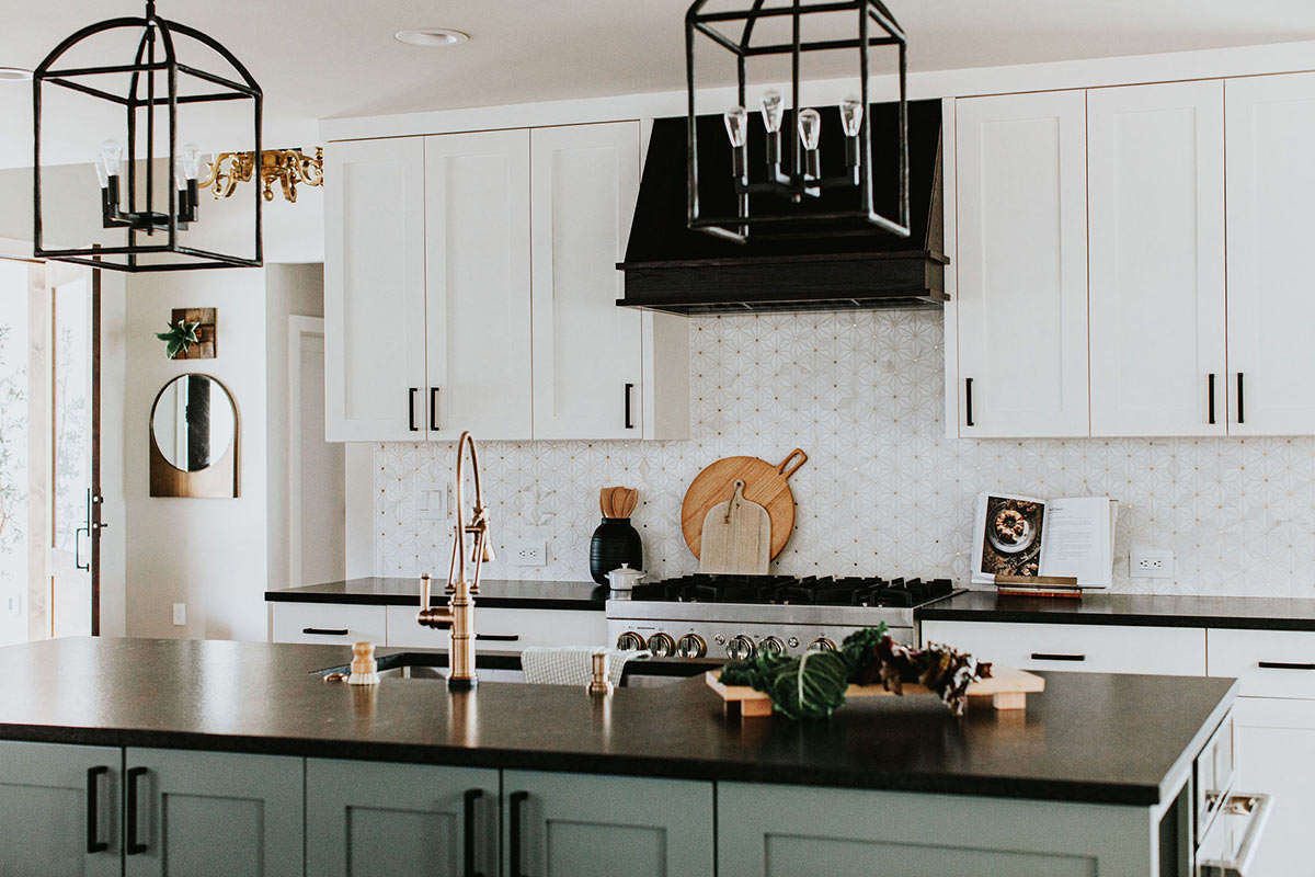 Modern farmhouse kitchen with green lower cabinets, white uppers, and lantern style pendant lights in Fort Collins Colorad