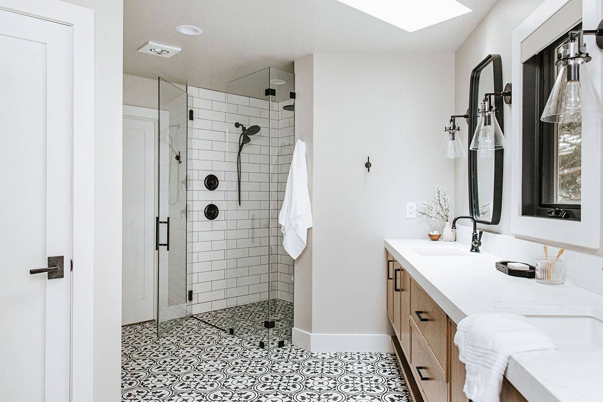 Black and white pattern tile floor bases white oak cabinets and a modern walk in shower in the Fort Collins home – interior design by J.Reiko Design + Co