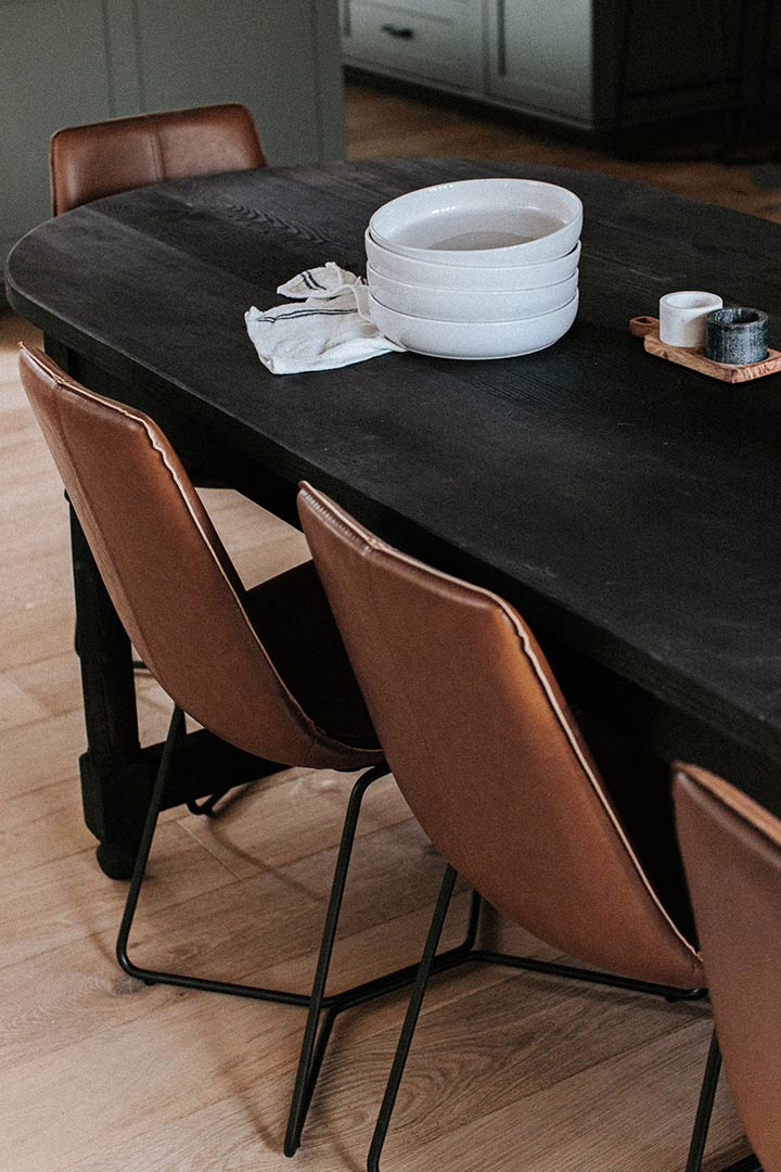 Leather chairs nest under a black farmhouse style table