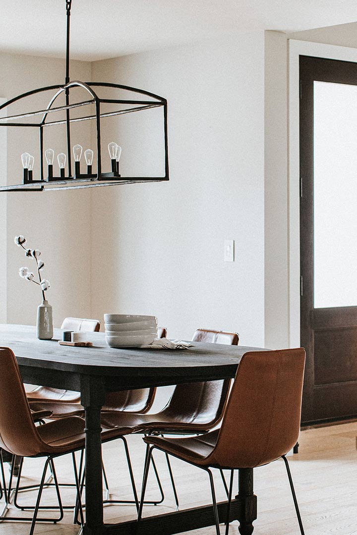 Modern Farmhouse dining room with a black table and leather chairs nestled next to the front door