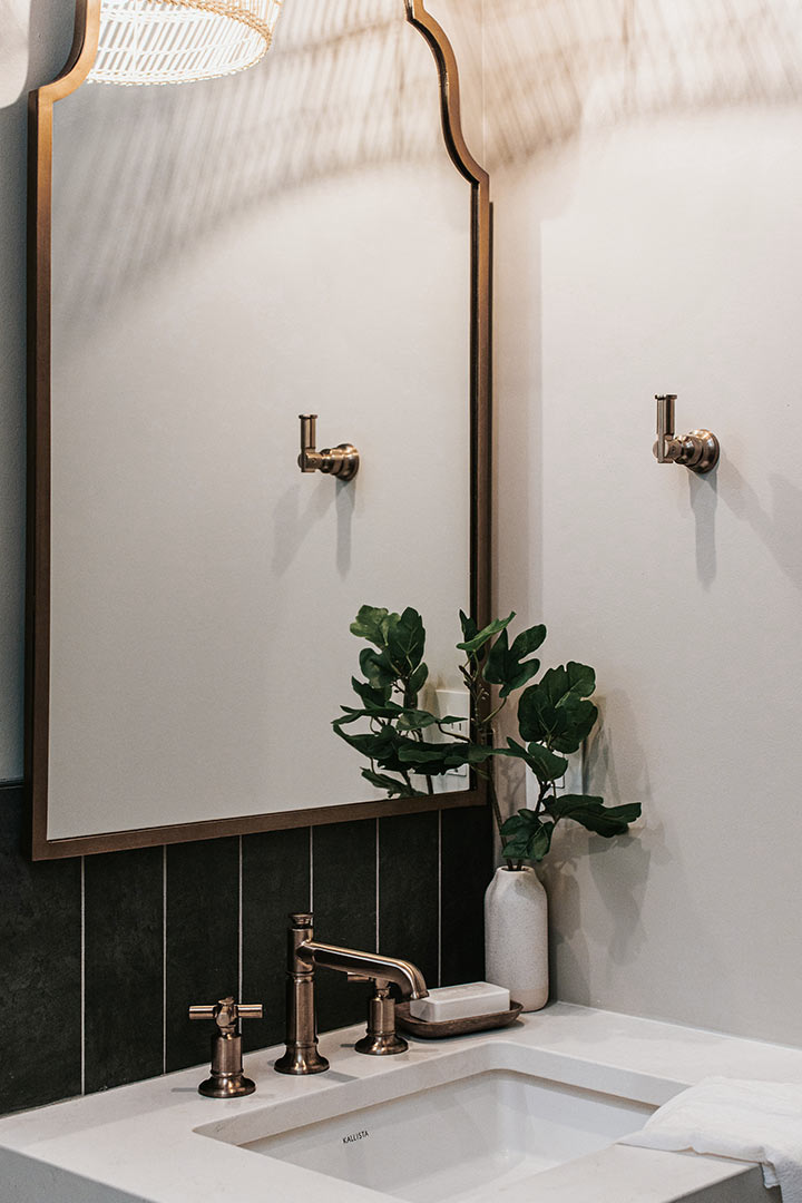 Brass framed mirro and Brass Brizo faucet of a hallway bath in Fort Collins Colorado designed by Jenny Murphy