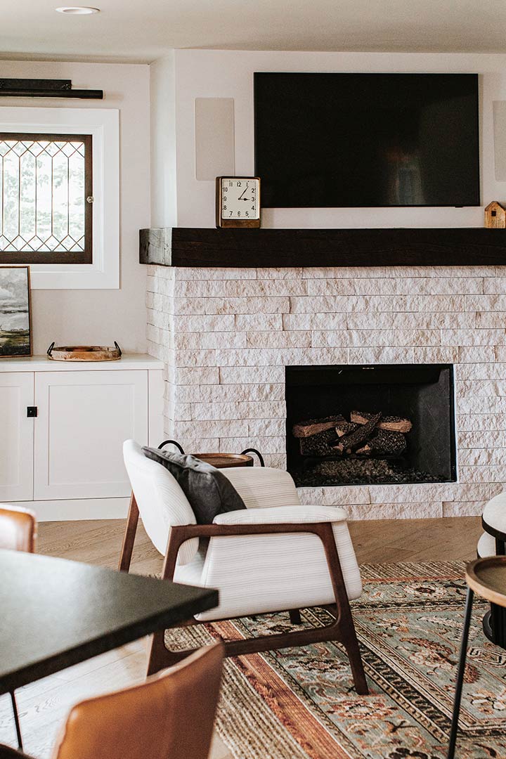 Natural stone fireplace with layerd rugs creates a cozy second living room of this modern farmhouse home in Windsor Colorad