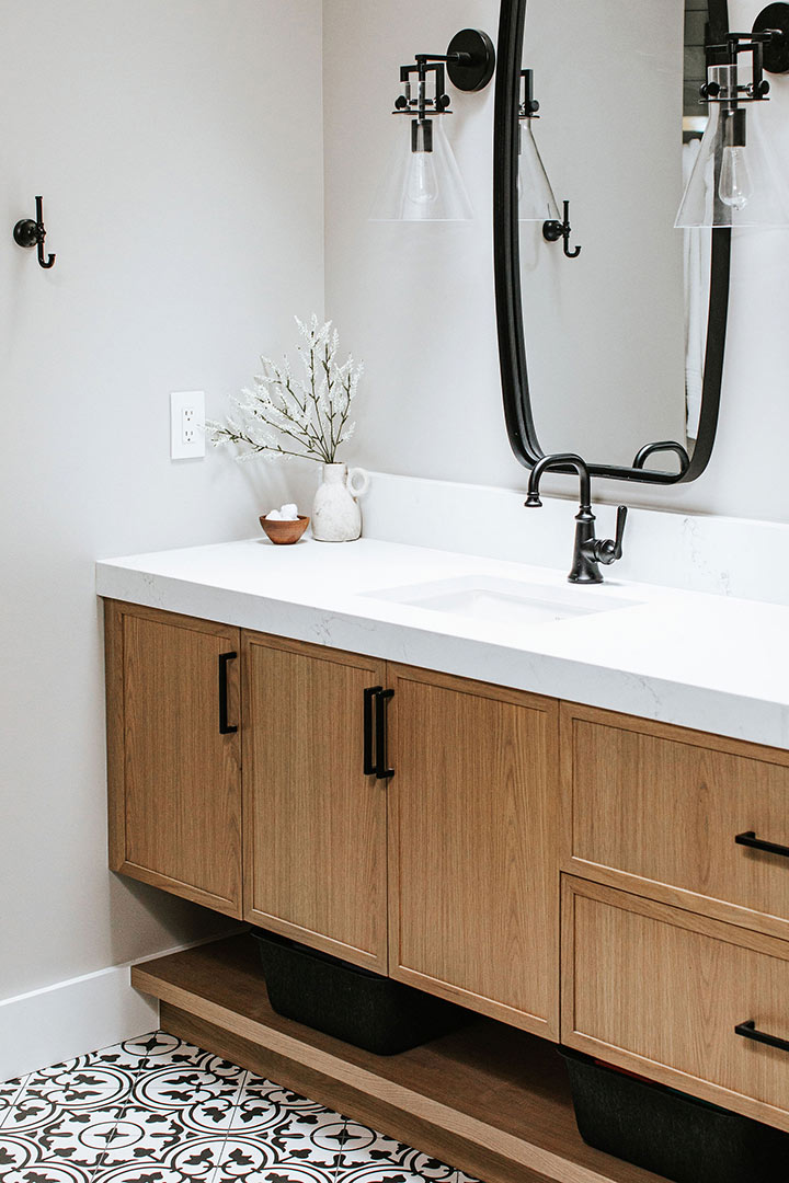 Black and white patterned tile with a white oak vanity and modern farmhouse style lights