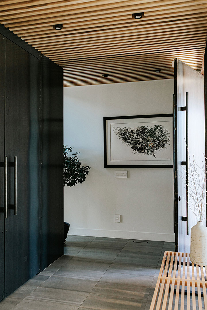 Right around the hall that leads to the staircase the modern wood slat and custom rolled steel entryway pairs well with the interior architechture created by J. Reiko Design + Co. 