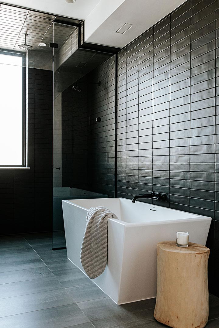 Japandi bath with a modern stand alone tub and walk-in shower with floor to ceiling matte black textured tile.