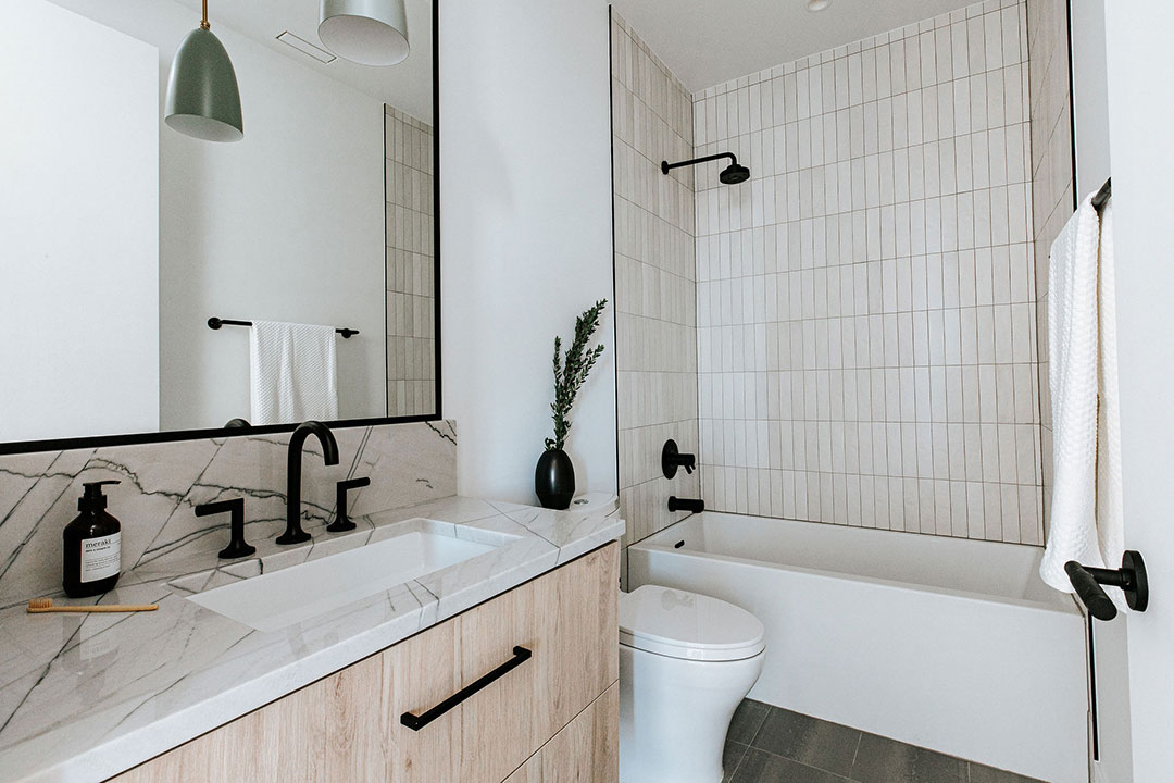 Japanese minimalist inspired bathroom layout with neutral toned tile, matte black fixtures and dark slate floor tile