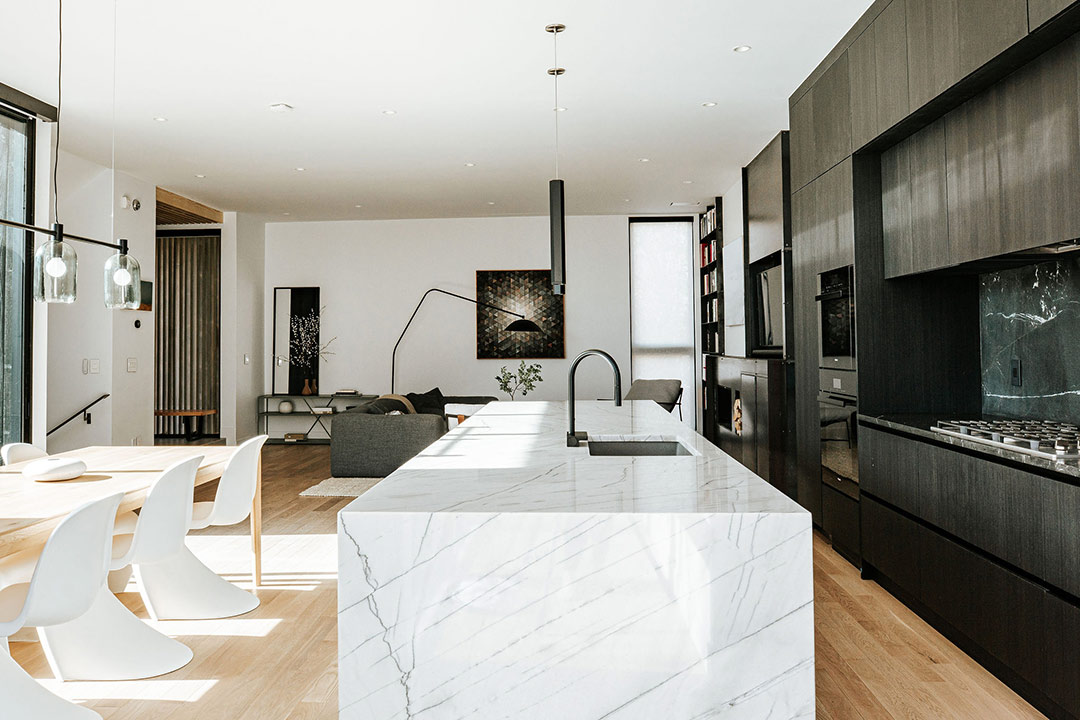 Beautiful and bright marble waterfall island countertops lay dead center of this overiew image of a modern minimalist kitchen in Denver Colorado
