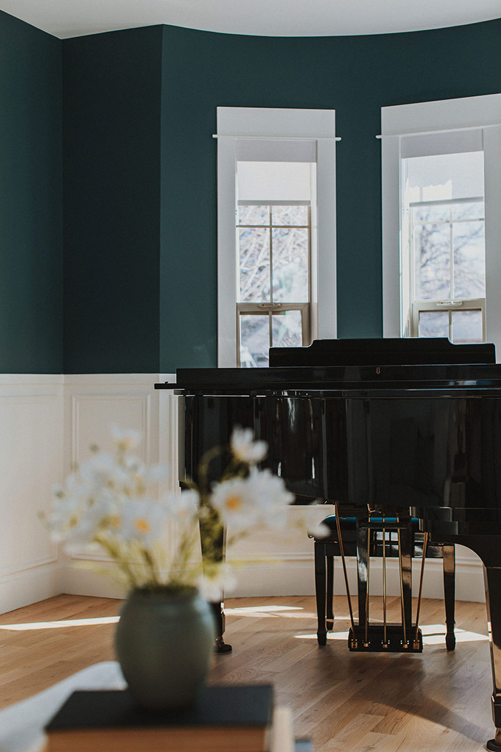 A modern piano room designed with accent blue wall paint and white oak floors