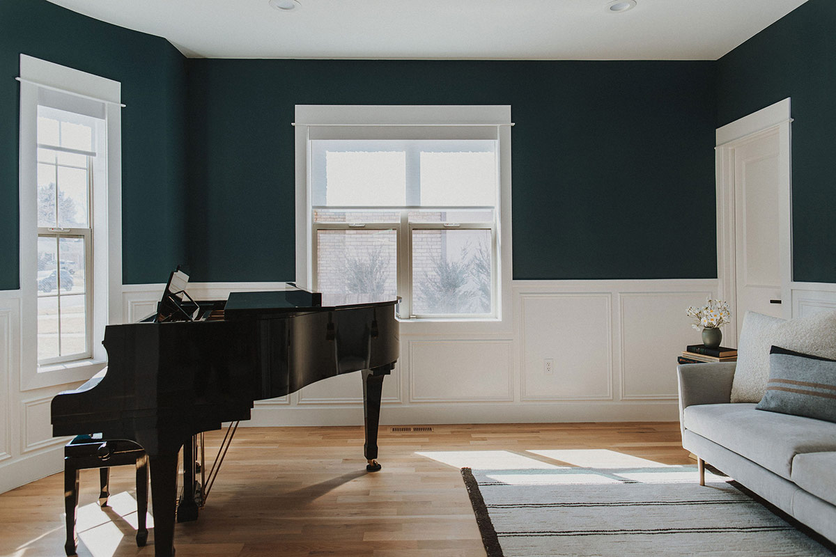 Minimalist piano room with blue accent walls highlights an all black classic piano which sits across from a modern sofa in this Denver Colorado home renovation.