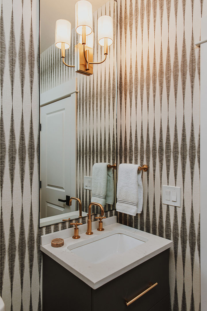 Magnolia Home wallpaper with contemporary brass bathroom fixtures in a modern powder bathroom renovation.