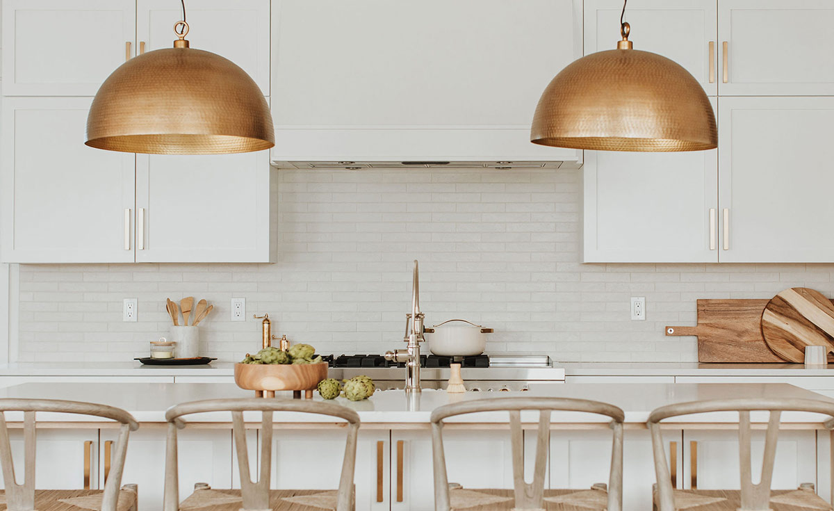 Modern brass dome pendant lights frame the kitchens sink and range in a bright and airy kitchen renovation design by J. Reiko Design + Co in Denver, Colorado