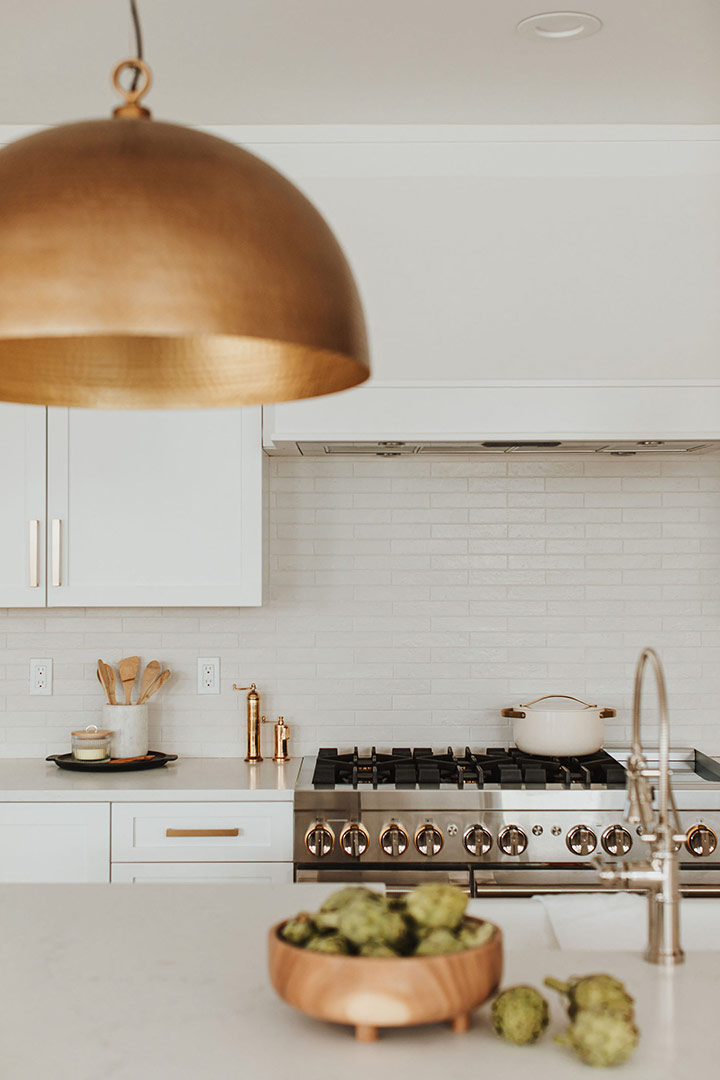 Modern hammered brass dome pendant light hangs over a quartz countertop of the newly renovated kitchen in Denver's Mayfair Neighborhood 