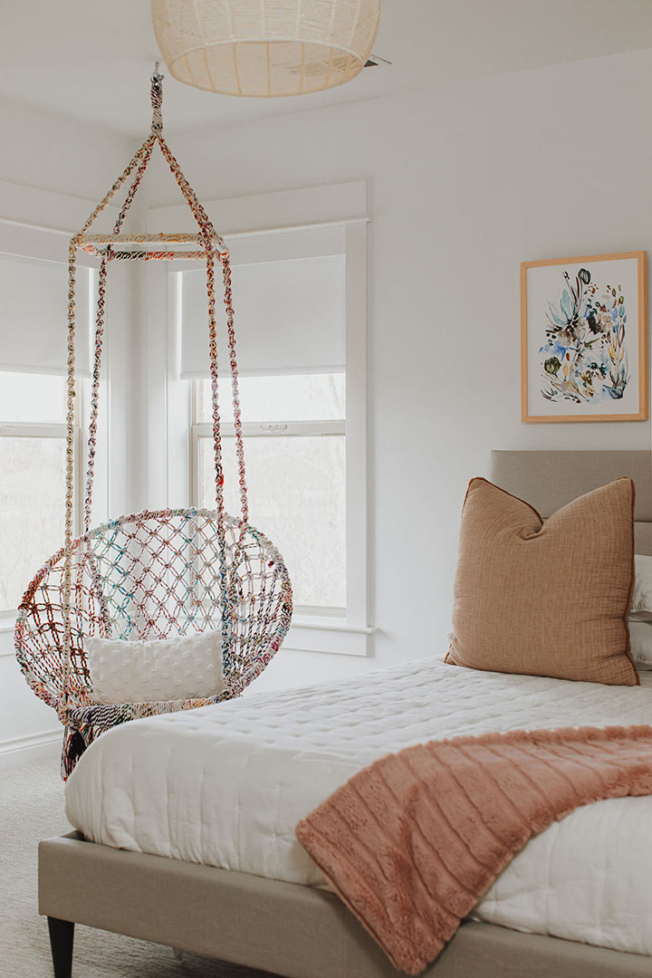 A hanging chair is featured in a teen girl or boy bedroom design with a woven lampshade and warm texture pairings.