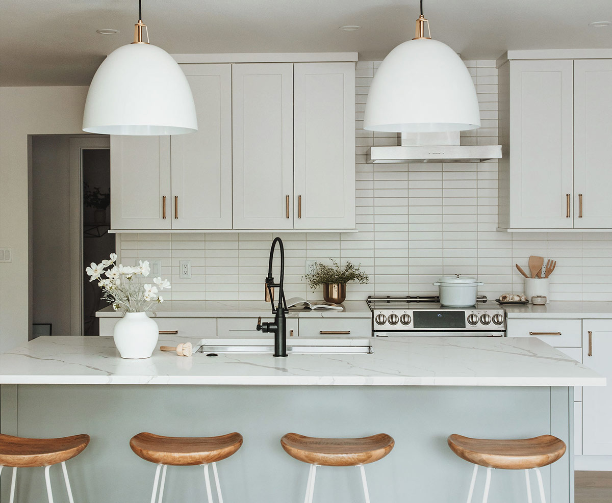 Scandinavian design kitchen with modern subway tile white shaker cabinets and warm wood barstools designed by J. Reiko Design + Co