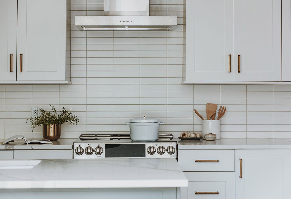 White minimalist kitchen remodel with brass cabinet pulls and white subway tile and white quartz countertops designed by J. Reiko Design + Co
