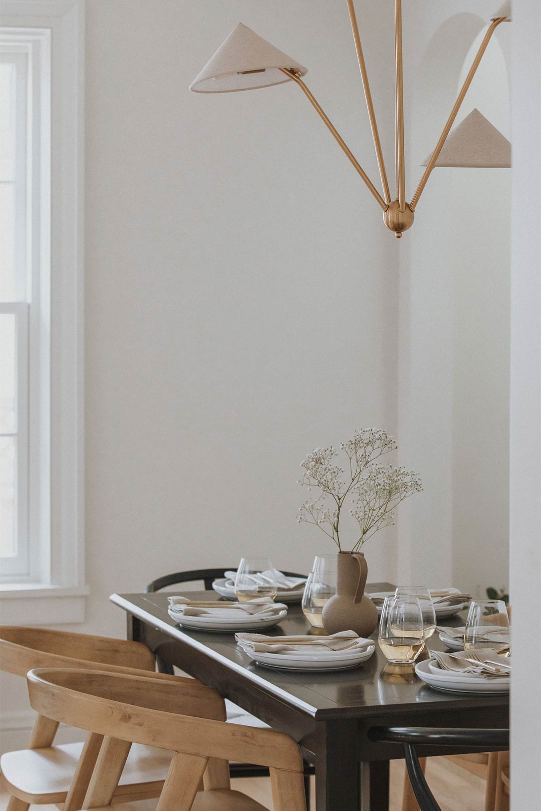 Amber Lewis for Anthropologie Mantis Chandelier paired with wishbone chairs and a dark modern dining table, styled by J. Reiko Design + Co