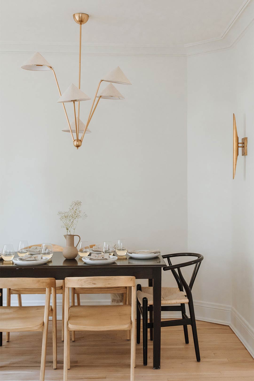Amber Lewis for Anthropologie Mantis Chandelier paired with brass sconce and white oak flooring