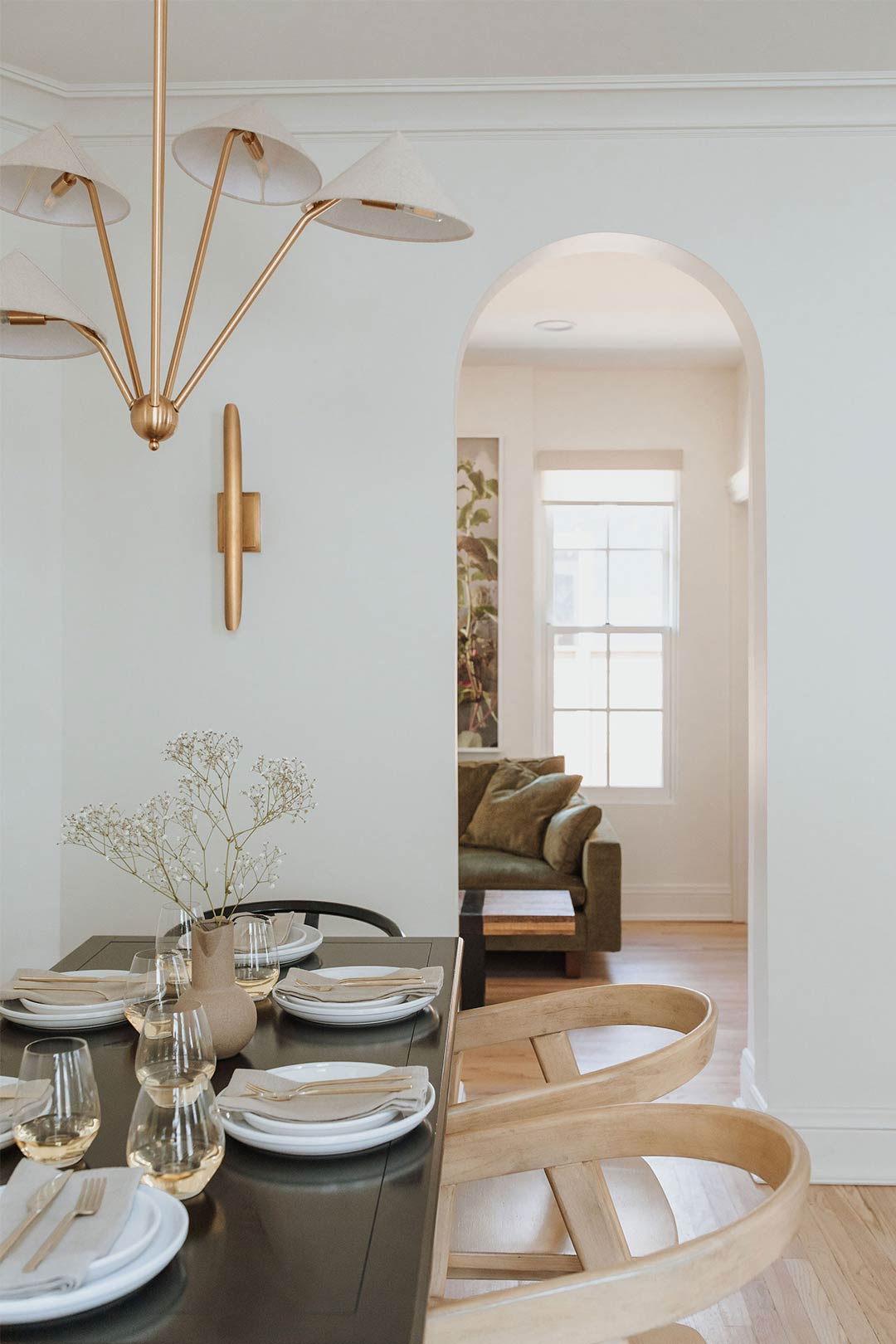 Amber Lewis for Anthropologie Mantis Chandelier paired with a modern brass sconce arched openings / doorways makes this organic modern remodel highlight it's historic Queen Anne features