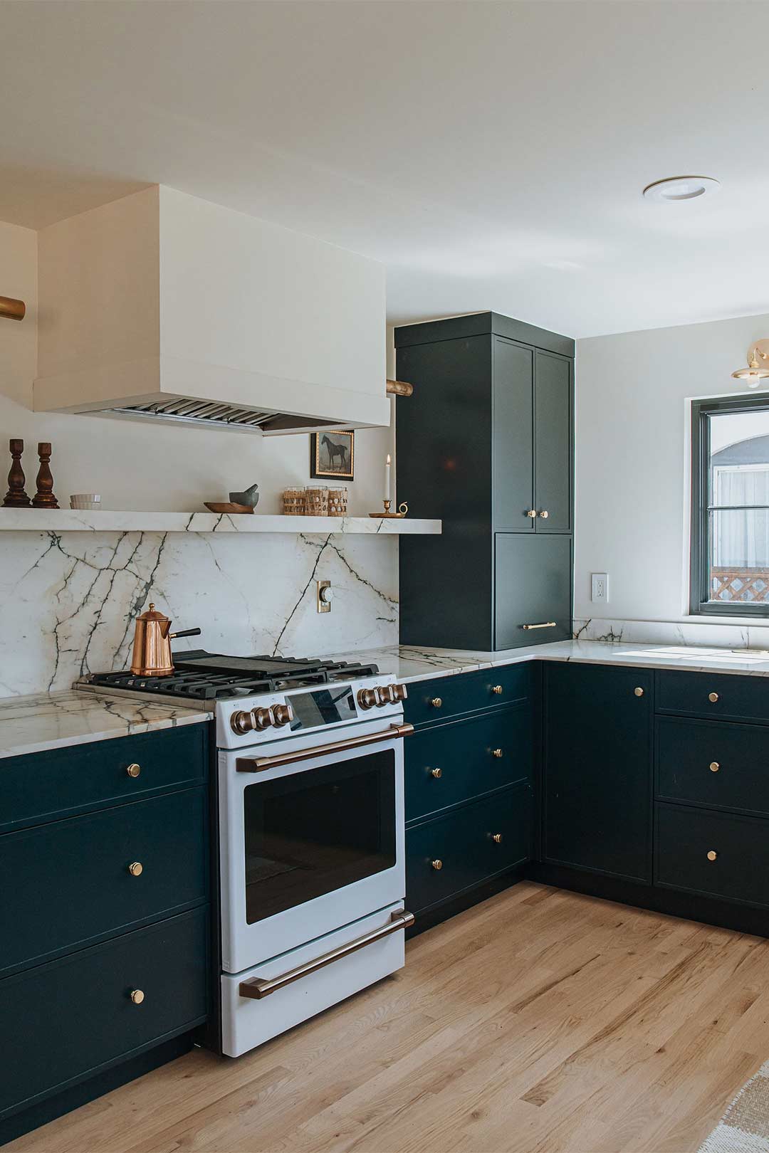 White oak flooring with dark blue cabinets with marble countertops and backsplash designed by Jennifer Murphy of J. Reiko Design + Co
