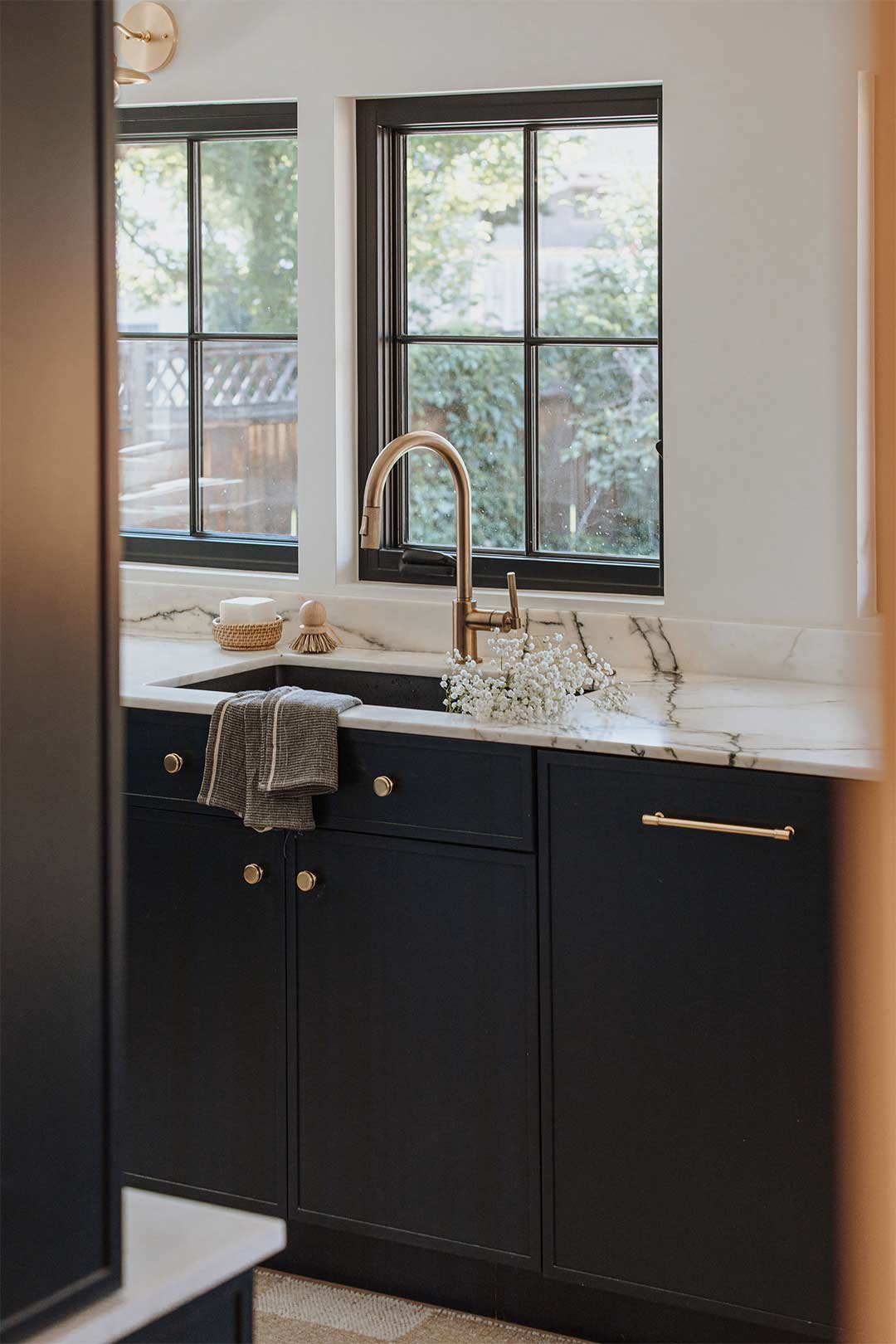 Transitional kitchen sink design in a historic remodel with dark blue cabinets, brass faucet and brass hardware in a Denver historic remodel.