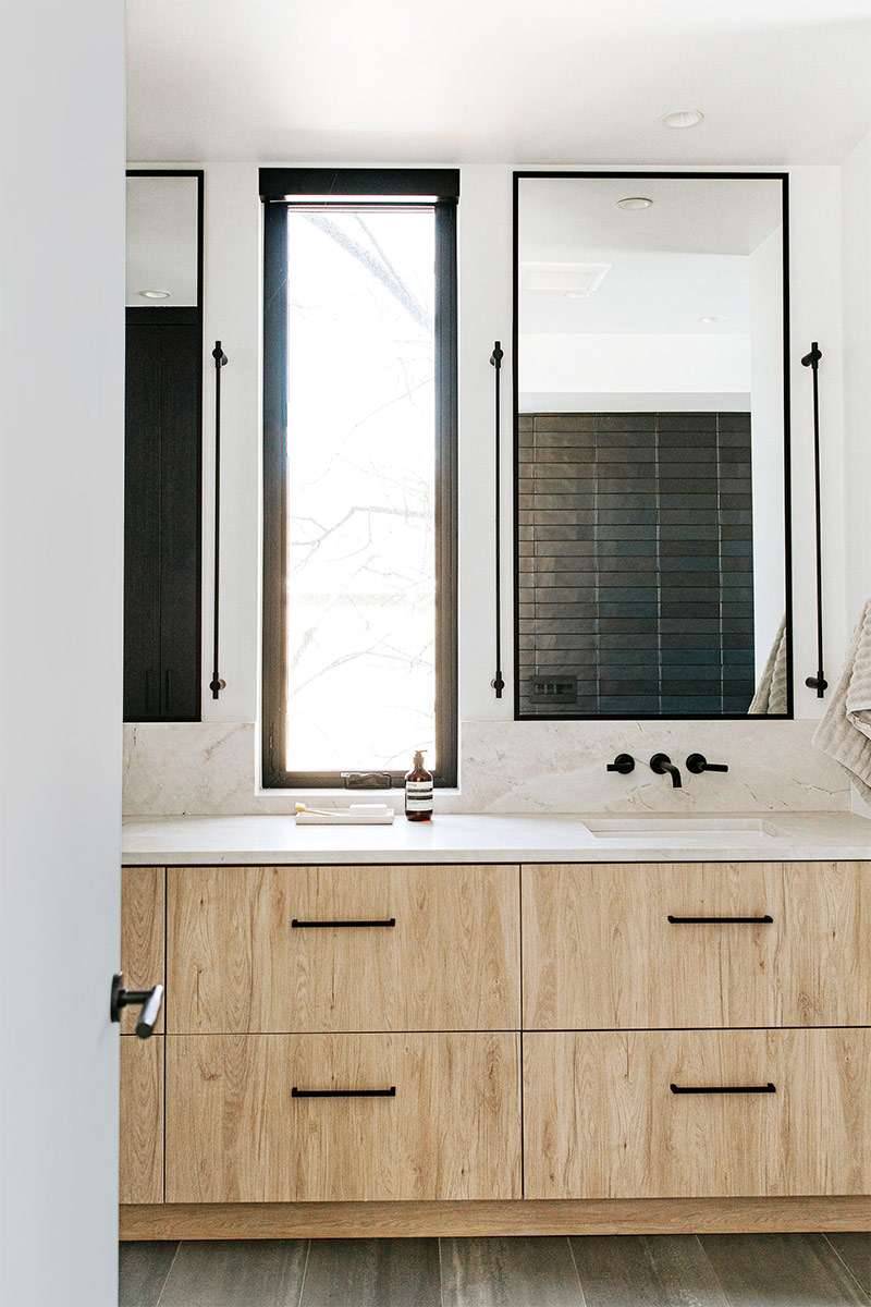 Japandi bathroom design by J. Reiko Design + Co with White oak double vanity matte black fixtures and a natural stone countertop and backsplash