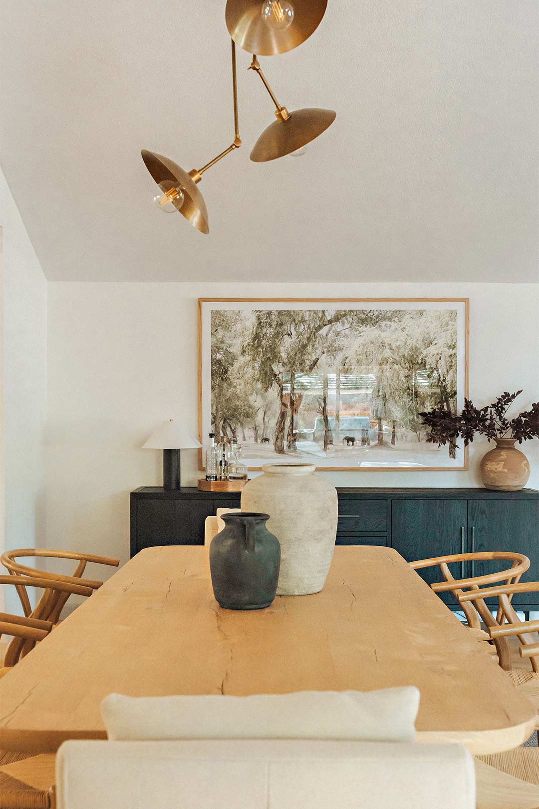 Domed Brass Pendant Lights and South African art  bring natural textures to this Modern Eclectic dining table