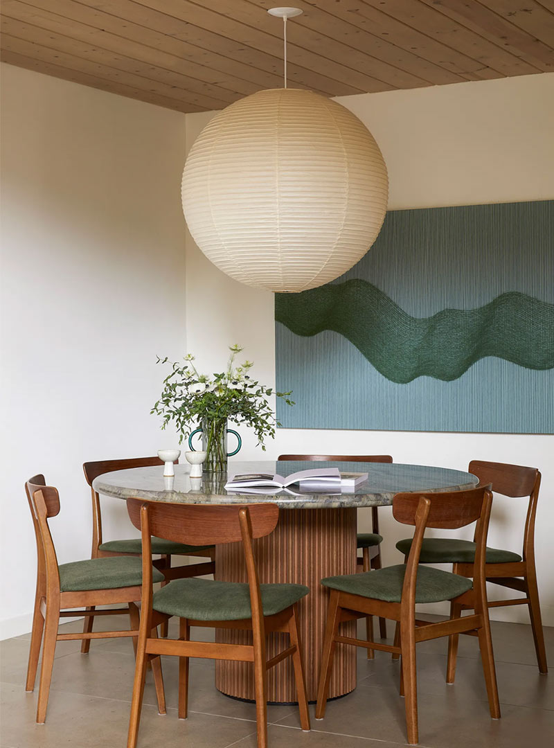 A Japandi dining table with Scandinavian styled wood back chairs and a large oversized Japanese-inspired globe pendant light, clearly melds the two styles together.