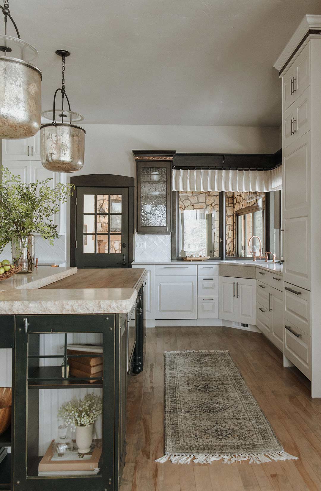 View of the island and the kitchen sink in a traditional kitchen with a dual butcher block and quartz countertop with off-white cabinets from Sherwin Williams in color SW6070 Heron Plume