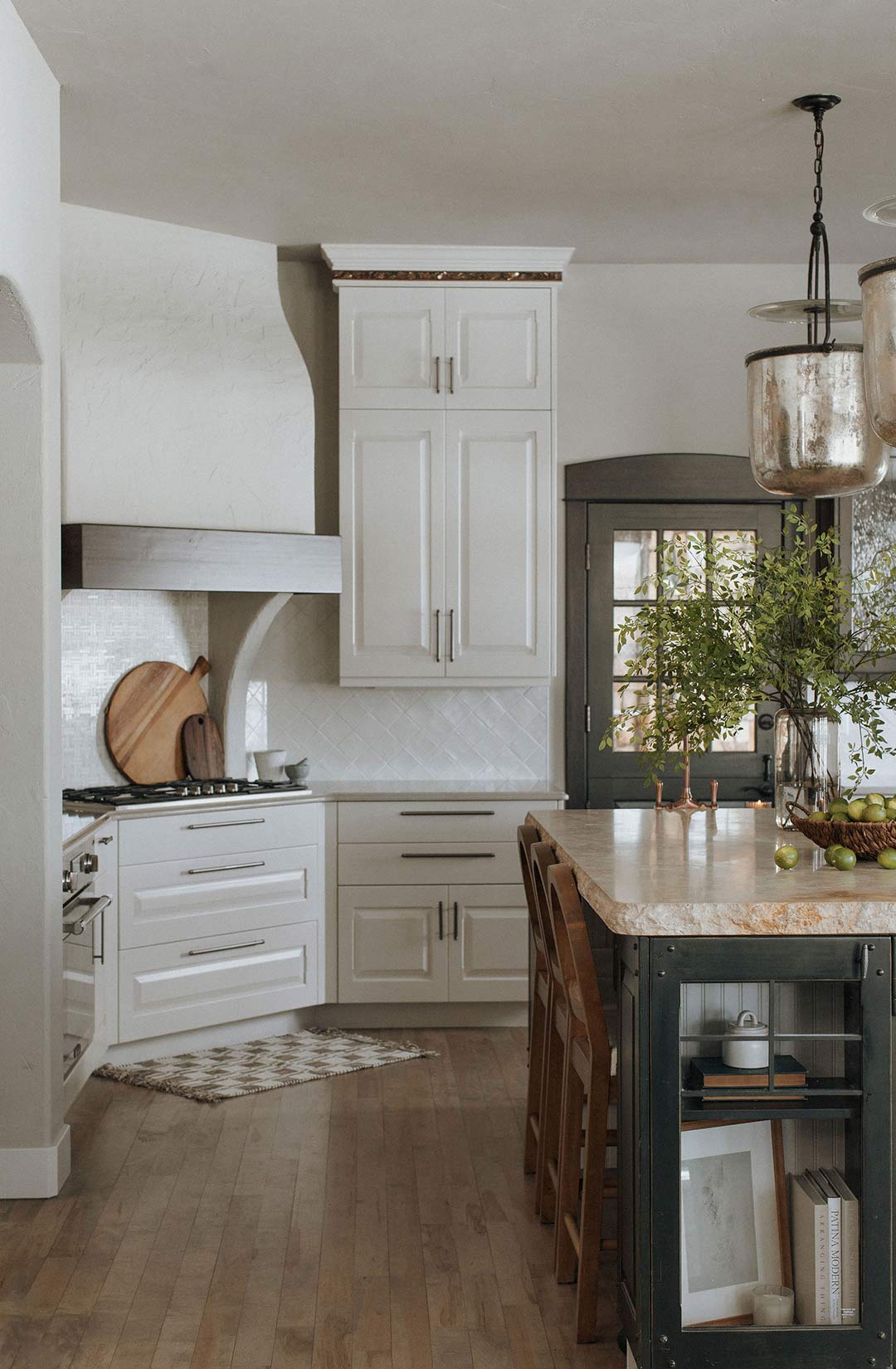 A plaster hood range with off-white cabinets is nestle next to the entrance of a custom Butler's pantry in this Traditional Kitchen in Fort Collins, Colorado.