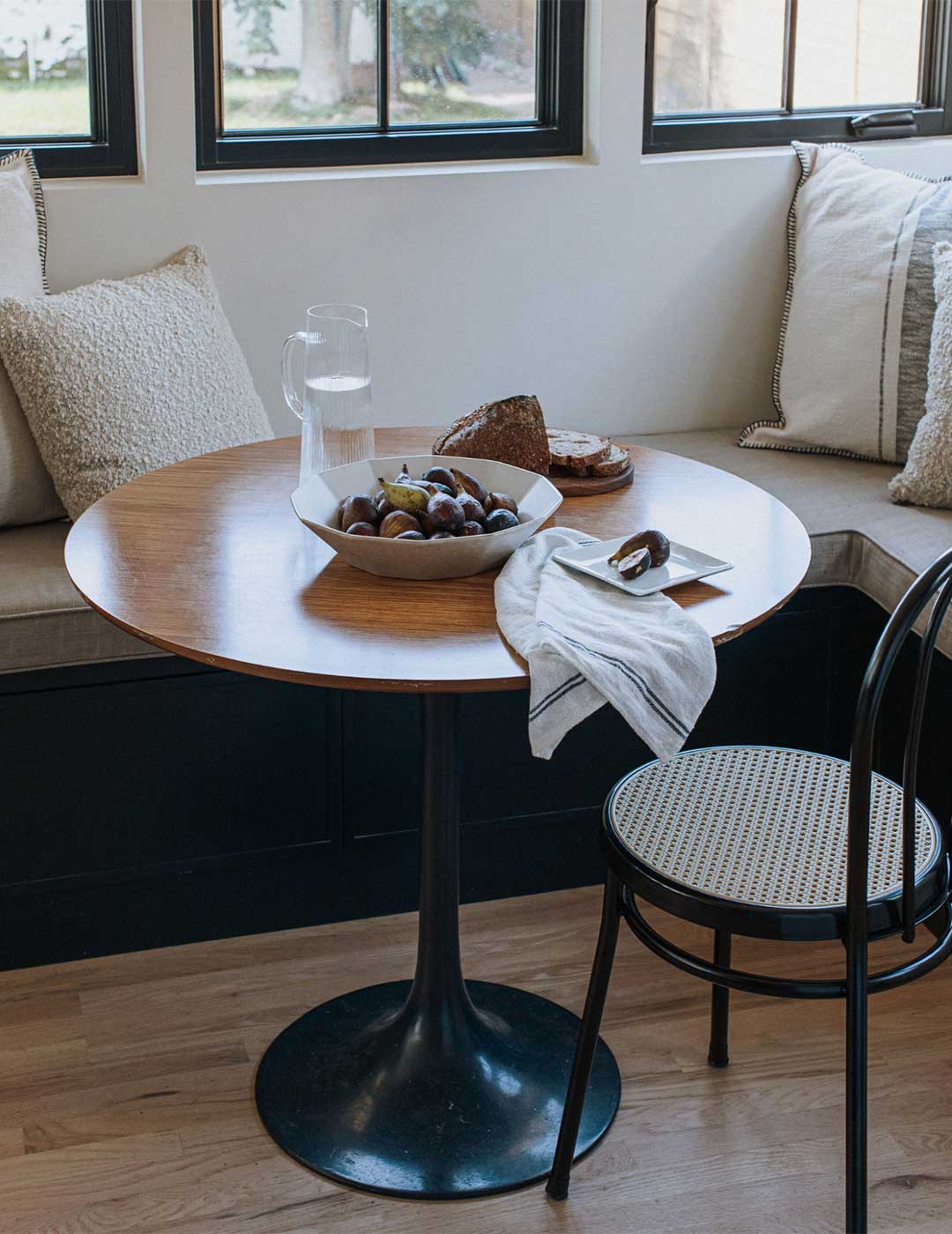 J. Reiko Design + Colonial Revival - 08 Historic remodel's dining nook with a dark blue bench seat brass pendant light overhead and black cane chairs styled by Jennifer Murphy of J. Reiko Design + Co