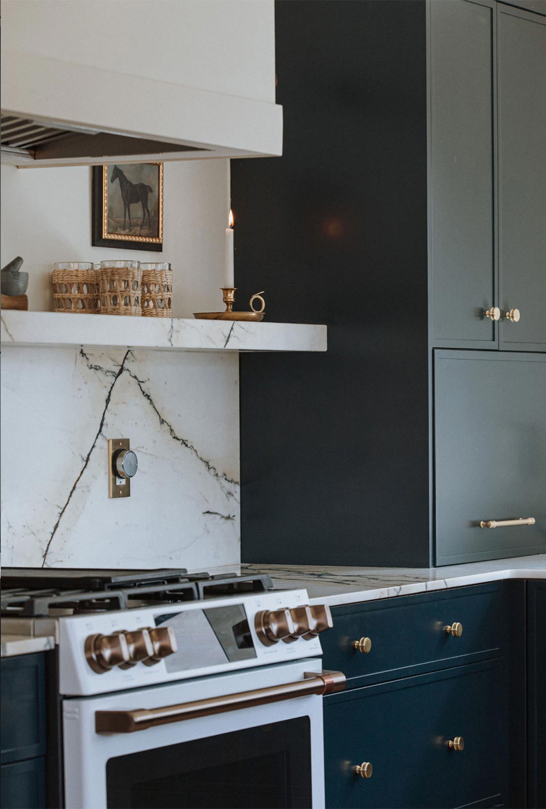 J. Reiko Design + Colonial Revival - 12 Blue cabinets with brass knobs and brass light fixture next to GE Cafe range in a historic Victorian house remodel