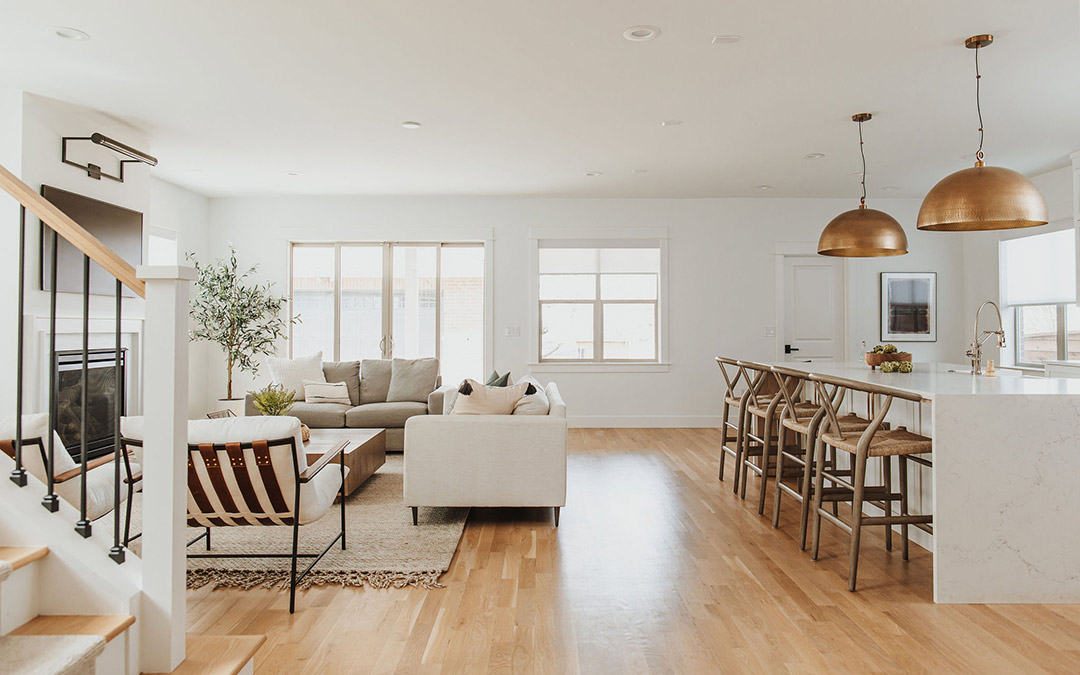 J. Reiko Design + Co. - Open vs. Closed Concept - 19 A wide angle view of an open concept living room design and connected kitchen island in this Mayfield Neighborhood home shows a modern minimalist living room with a glimpse of a modern stair rail and waterfall quartz countertop island with wishbone backed barstools