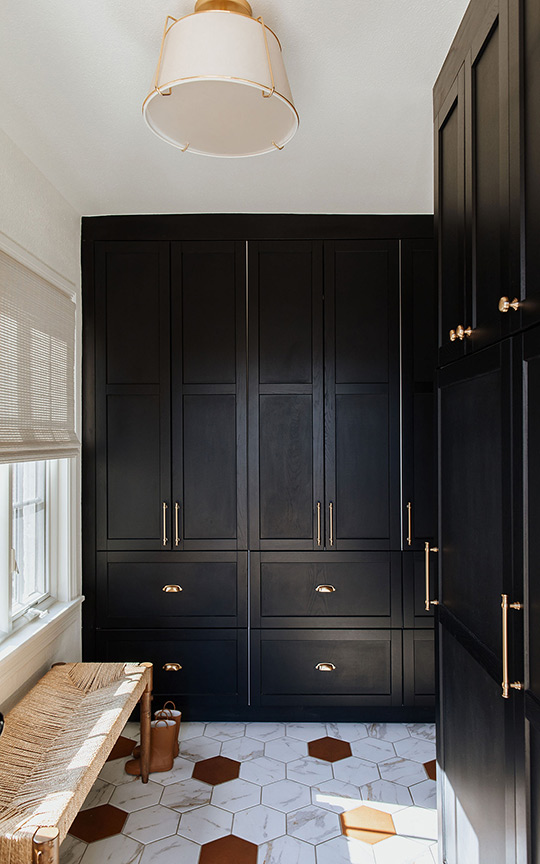 J. Reiko Design + Co. - Selecting Finishes - 11 A modern mudroom of a home renovation design by J. Reiko Design + Co. Dark floor to ceiling cabinets are accented by brass pull and knobs that tie into the drum ceiling light above.