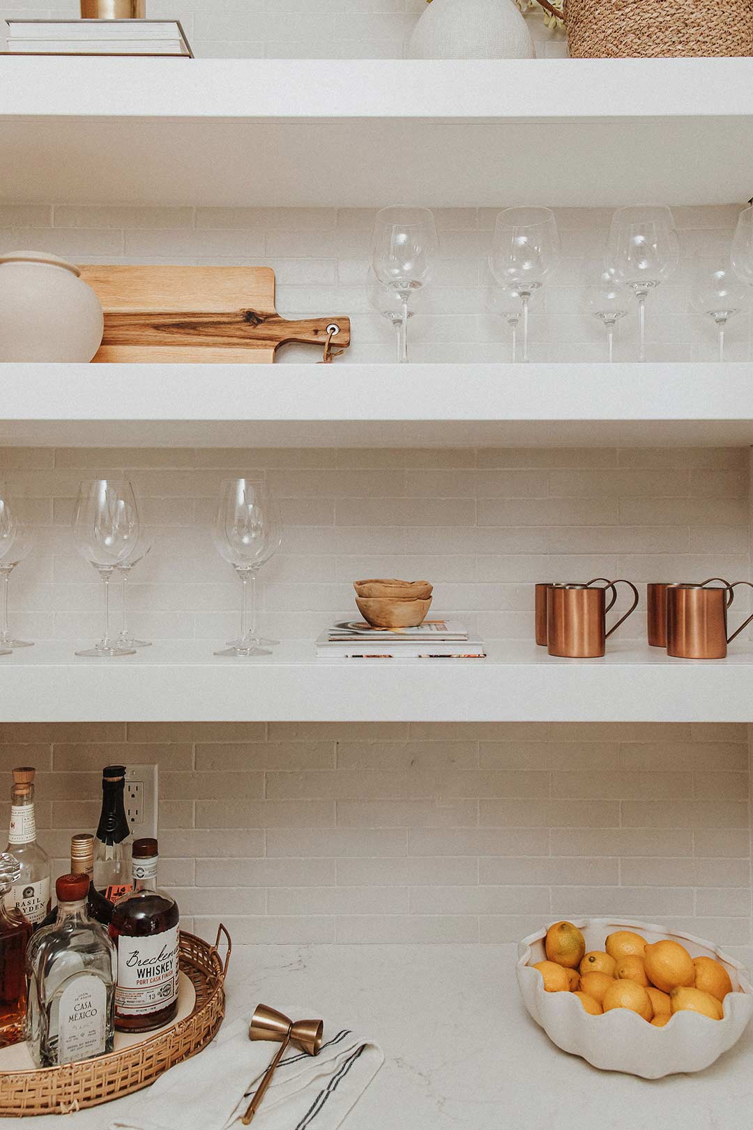 J. Reiko-Design + Co. - Working Pantry - 6 Bright white open shelved styled by J. Reiko Design + Co. features a tray of liquors, wine glasses and an assortment of natural textured objects.