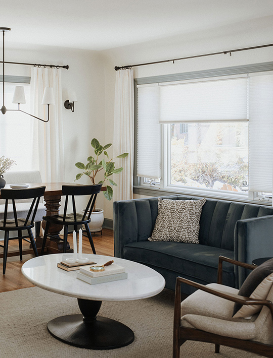 J. Reiko Design + Co. - Asymmetrical Rooms - 05 Living and dining area with an off-centered sofa balanced by a sculptural chair, layered lighting, and a variety of light and dark tones with natural textures.